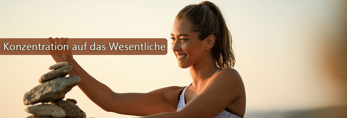 Junge Frau stapel und balanciert Steine. Beschriftung: Konzentration auf das Wesentliche.